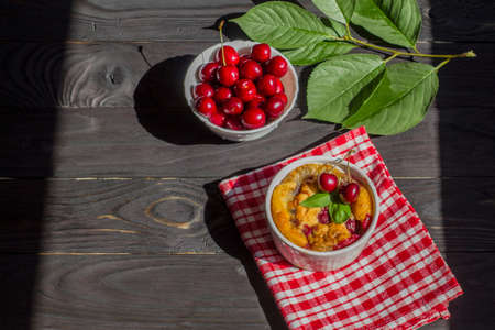 A portioned plate with clafoutis on a wooden background on a bright sunny day. Traditional French pie with cherry clafoutis. Top viewの写真素材