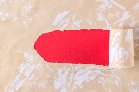 Background with a red hole in the paper with coffee stains. Curled up torn coffee paper on a red background. Breakthrough paper. Layout template.の写真素材