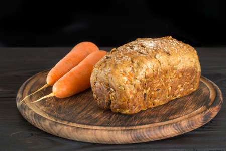 Loaf of healthy carrot bread on a round wooden boardの写真素材