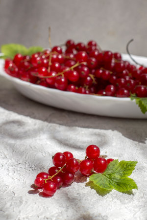 Bunches of red currants on a light table on a bright sunny day.