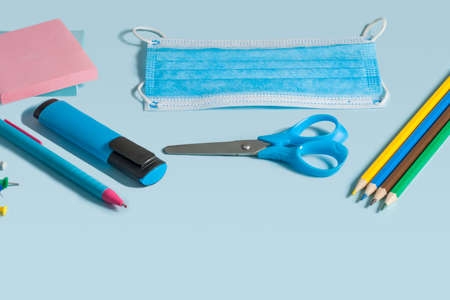 School stationery and medical masks on desk, keep your distance, open school