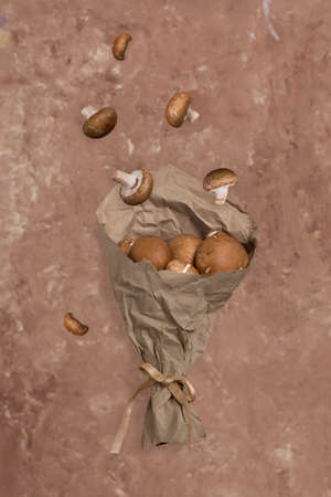 Flying food. Flying mushrooms champignons in paper packaging on a beige background. Royal brown...