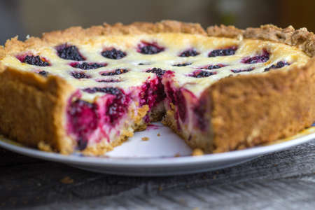 Blackberry pie on a wooden background in a cut.