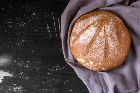 Round loaf of buckwheat bread on dark background. Top view