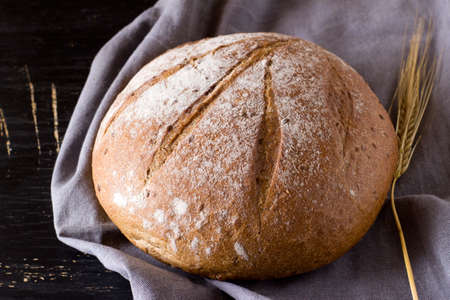 Round loaf of buckwheat bread on dark background. Top view