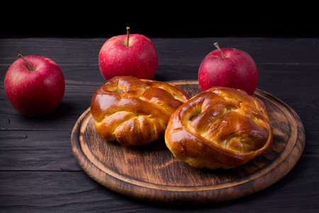 Baked yeast buns with apple on wooden board on dark background.の写真素材