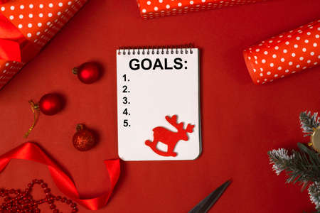 Goals for 2022 on a blank sheet of paper, among Christmas gifts on a red background. Concept of the upcoming christmas holidaysの写真素材