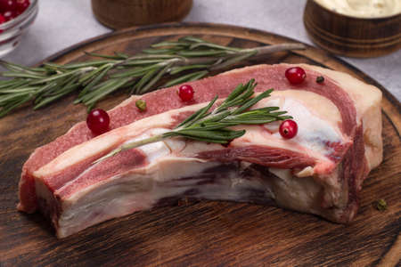 Piece of fresh raw beef brisket on the bone with cranberry rosemary on dark wooden background.の写真素材