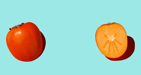 Cutaway persimmon on an blue background with hard shadows. Healthy food and nutrition conceptの写真素材