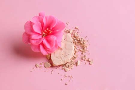 Face powder. Broken pieces of cosmetic powder with a pelargonium flower. Cosmetic smear. Make up a crushed powder.の写真素材