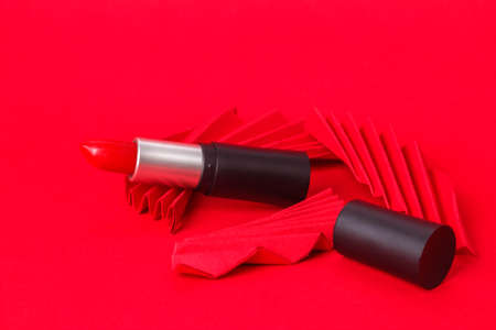 Red lipstick with paper craft on red background. Creative concept photo of cosmetics with hard shadowの写真素材