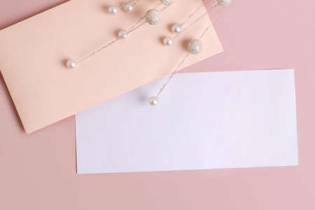 Mockup with a rectangular envelope and a sheet of paper on a pastel pink background. Template for branding and advertisingの写真素材