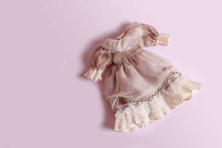 Beautiful vintage dress with ruffles for a doll on a pink background with copy space.の写真素材