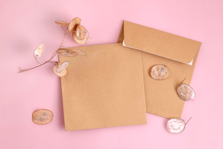 Invitation or greeting card mockup with craft envelopes on soft pink background.