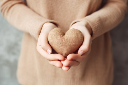 Female hands holding heart on gray background, closeup. Charity conceptの素材