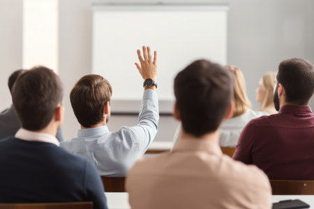 Rear view of businessman raises his hand during a presentation at meeting in officeの素材
