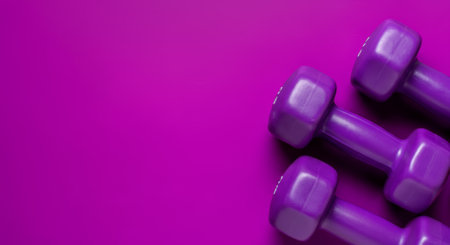 Purple dumbbells on vibrant pink background for fitness and exercise.の素材