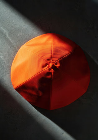 Cardinal's scarlet wool biretta (square cap) on a cool gray stone surface, symbolizing the authority and tradition of the College of Cardinals.の写真素材