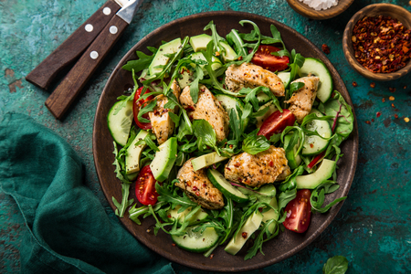 roasted chicken, avocado, tomato, cucumber and arugula salad, top view, green backgroundの写真素材