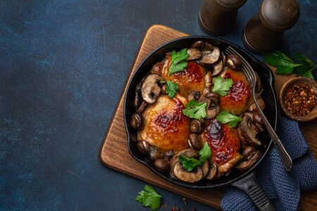 roasted  chicken thighs with mushrooms on cast iron  pan , dark blue concrete background, top view, copy spaceの写真素材