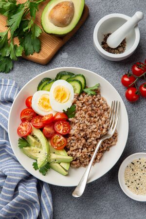 healthy vegan lunch bowl with avocado, egg, cucumber, tomato and buckwheat, top viewの写真素材