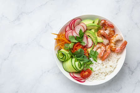 Avocado, prawn, cucumber, tomato, radish, carrot and rice salad bowl. Healthy food.  White background, top view, copy spaceの写真素材