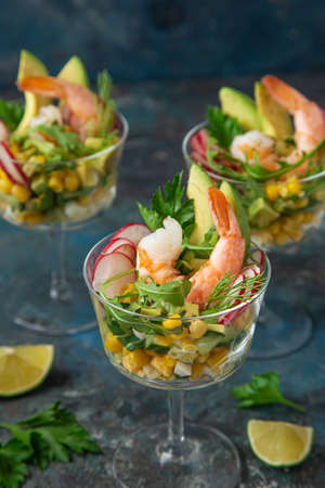 Prawn and avocado salad cocktail in glass, selective focus, dark blue backgroundの写真素材