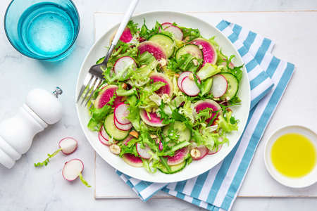 Fresh vegan watermelon radish and  cucumber salad on white plate, top viewの写真素材