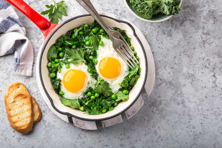 fried eggs with kale, spinach and green peas for breakfast, top view, copy spaceの写真素材