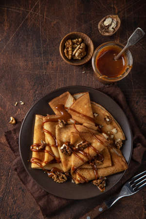 crepes with salted caramel and nuts, selective focus, wooden background
