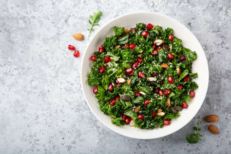 fresh kale, roasted chickpeas, almond and pomegranate salad in white bowl, healthy vegan food, top view, gray background, copy spaceの写真素材