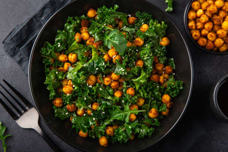 vegan healthy kale and roasted chickpeas salad in black bowl, top view, dark backgroundの写真素材