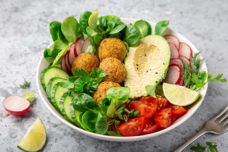 salad with avocado, falafel, cucumber, tomato and redish, healthy vegan lunch bowl, selective focusの写真素材