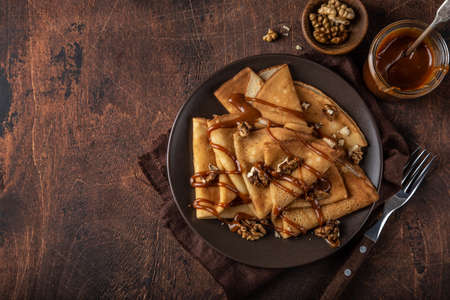 crepes with salted caramel and nuts, top view, wooden background, copy spaceの写真素材
