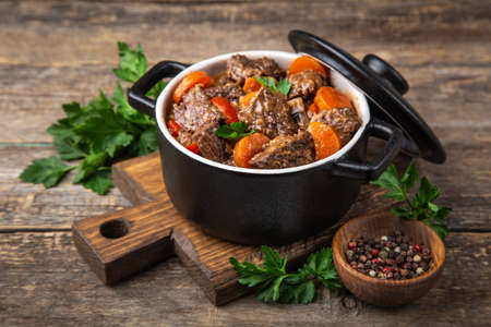 beef stew with vegetables in black pot on dark wooden background, selective focusの写真素材