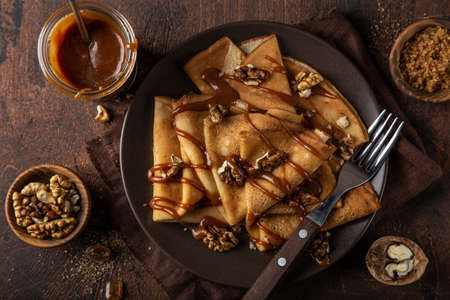 crepes with salted caramel and nuts, top view, wooden backgroundの写真素材
