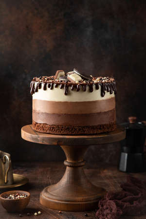 no baked layered cheesecake Three Chocolates on cake stand, wooden background, selective focusの写真素材