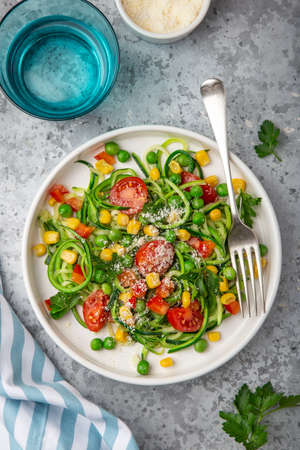 zoodle (zucchini noodle) with vegetables on white plate, healthy vegetarian food, top viewの写真素材