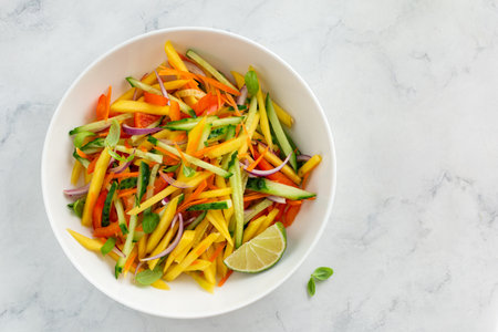 mango, carrot and cucumber salad on  white bowl, top view, copy spaceの写真素材