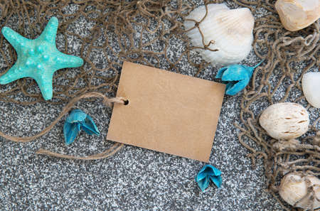 Paper card on the white and black sand with sea shells and starsのeditorial素材