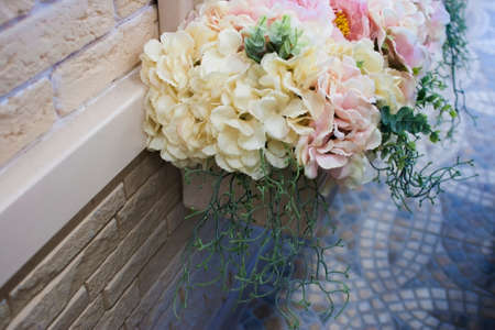 Yellow and pink flowers in a pot on a wall
