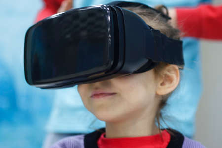 A child in virtual reality glasses makes a walk with dinosaurs