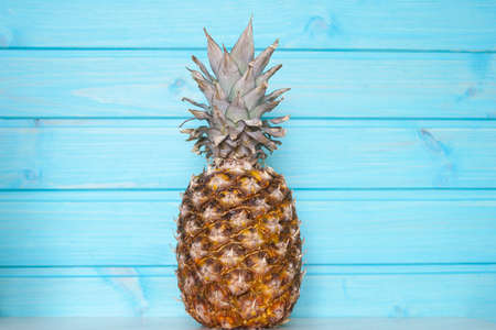 Ripe pineapple on a background of bright blue wooden wall