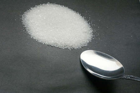 Sugar drug of our time. The spoon next to the hill of the white beet sugarの写真素材