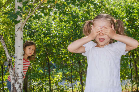 Two sisters playing hide and seek in the parkの写真素材