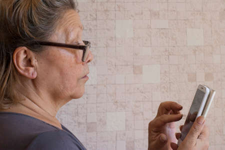 Elderly lady is learning to use her smartphoneの写真素材