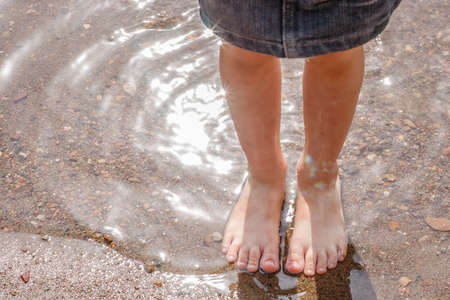 The feet of a child in the warm clear water of the lakeの写真素材