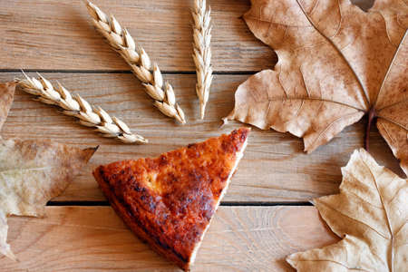 Autumn still-life of a dry maple leaves and slice of warm homemade pie.