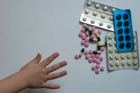 Danger: the child reaches for the pill. Safety rules when the baby is at homeの写真素材