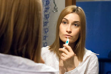 Girl performs morning oral hygiene at the mirrorの写真素材
